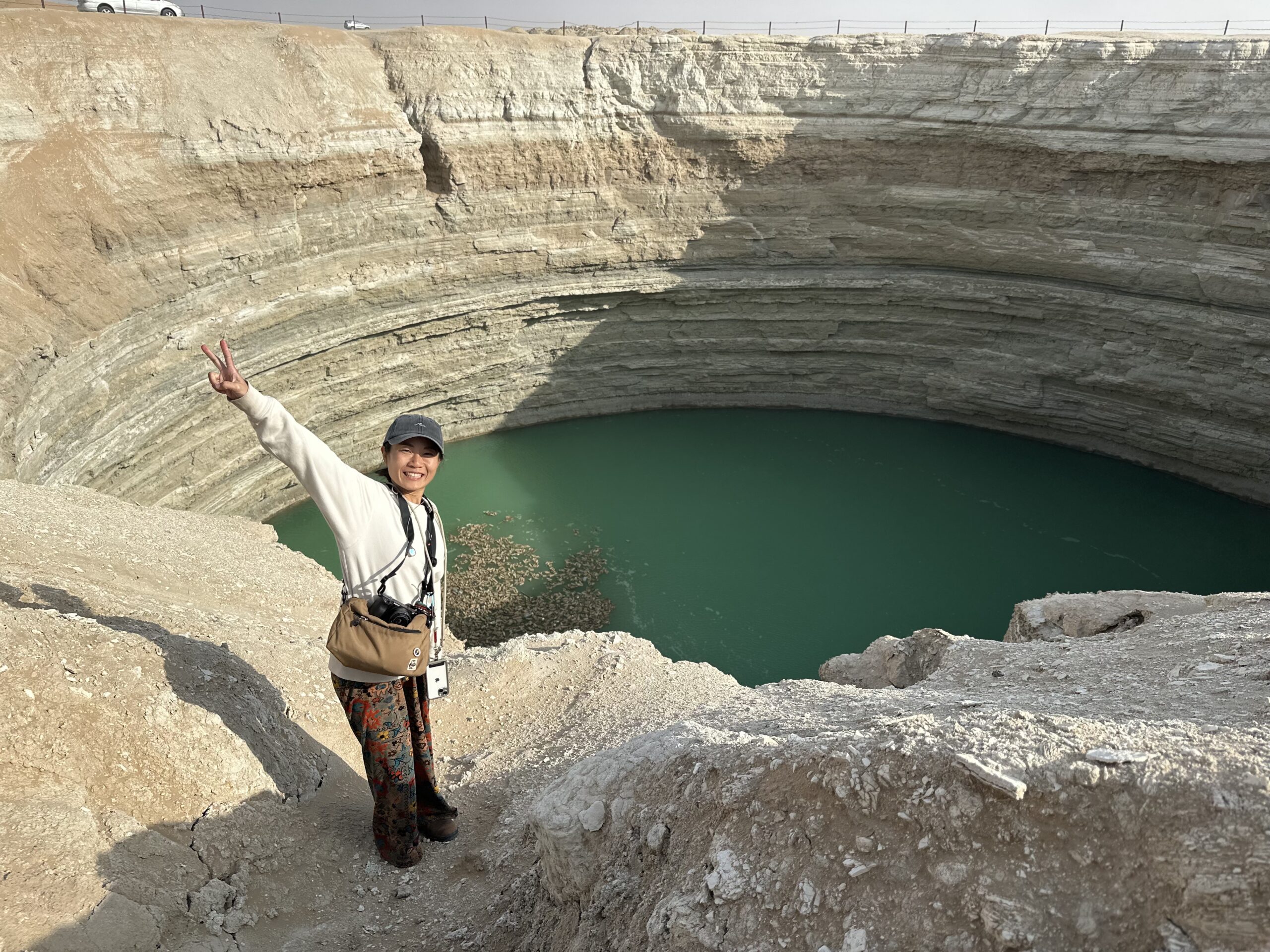 3-Day Tour: Farap ↔ Shavat via Merv, Ashgabat, Darvaza & Kunya-Urgench Japanese tourist Yuka posing beside the Water Crater near Darvaza in the Karakum Desert, Turkmenistan