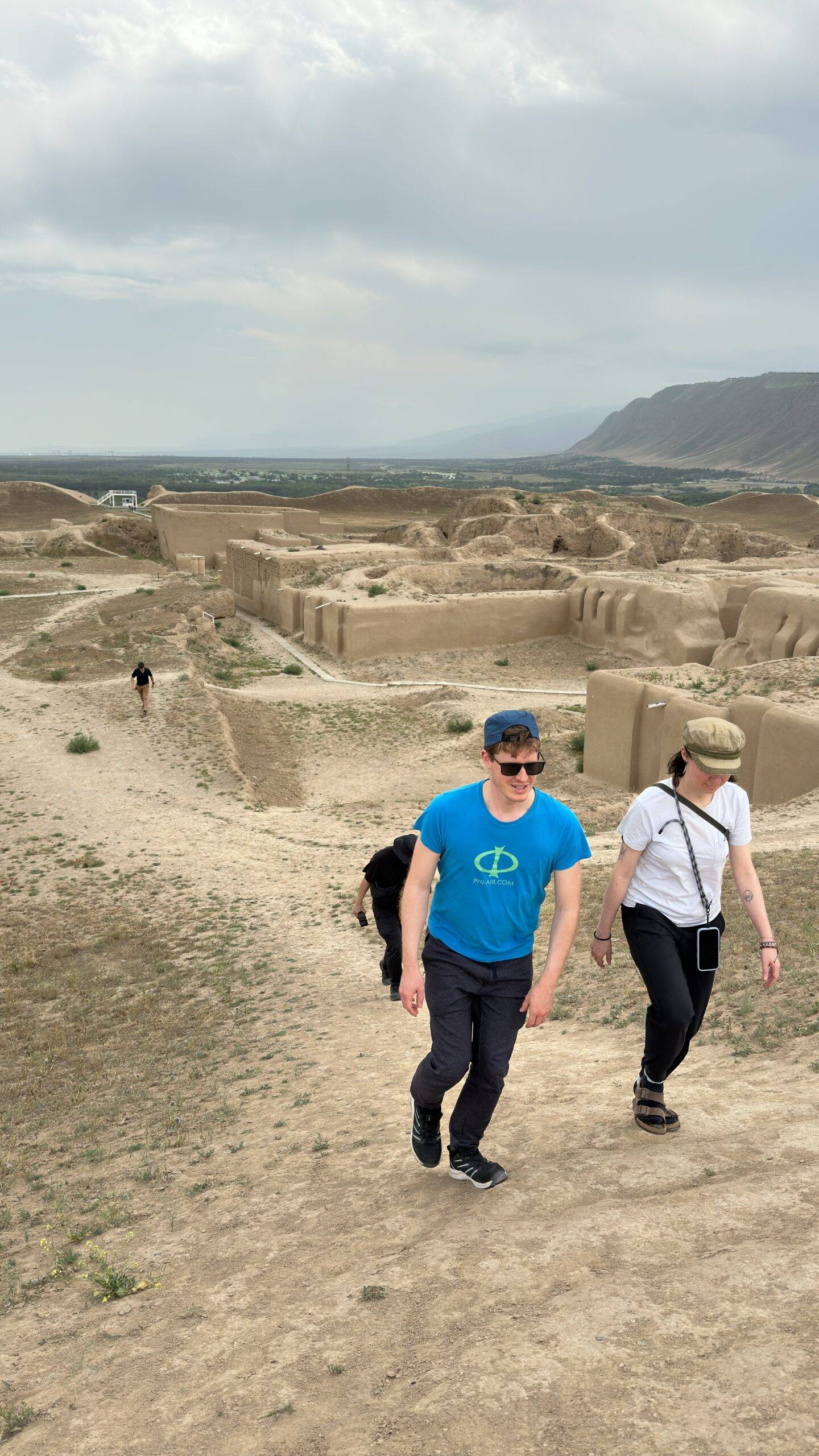 3 Day Turkmenistan Tour from Ashgabat: Darvaza & Night Train to Bukhara Travelers walking among the mud-brick ruins of Old Nisa with the Kopet Dag Mountains near Ashgabat, Turkmenistan
