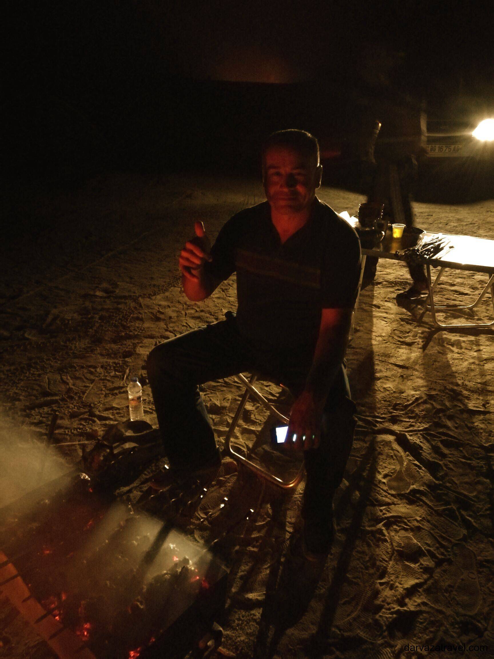 Darvaza Yurt Camp Local driver cooking kebab at night under simple conditions at Darvaza Yurt Camp