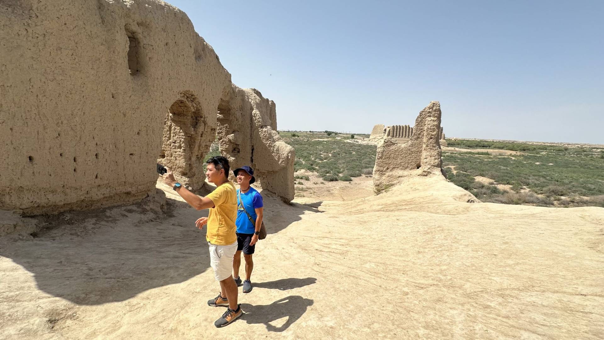 4 Day Turkmenistan Tour: Farab to Shavat via Merv, Ashgabat & Darvaza Malaysian travelers exploring the weathered mud-brick chambers of Small Kyz Kala with Great Kyz Kala visible in the distance at Ancient Merv