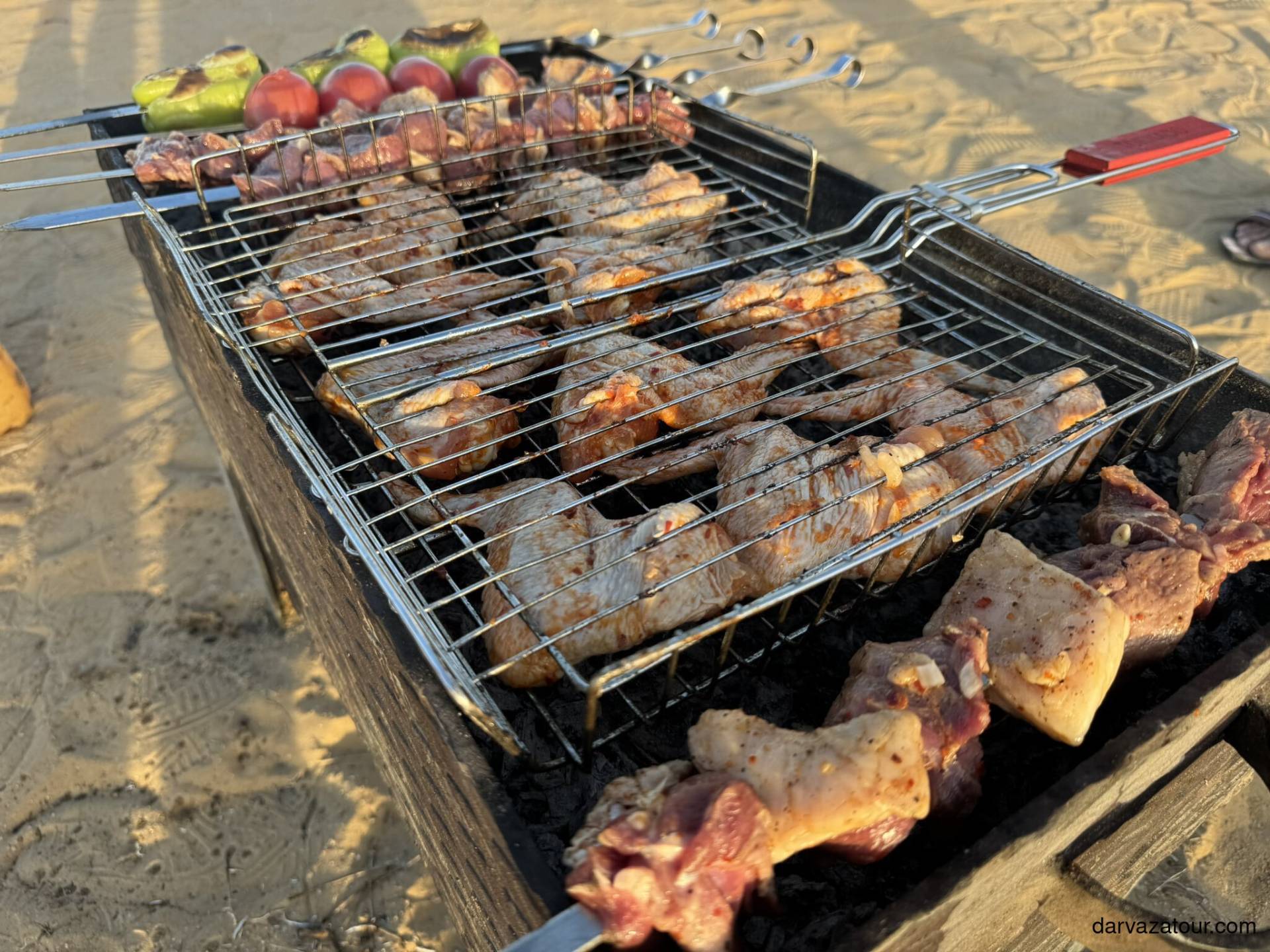 Darvaza Yurt Camp Barbecue preparation in Darvaza – lamb, chicken wings, and vegetables grilling over open fire in the desert