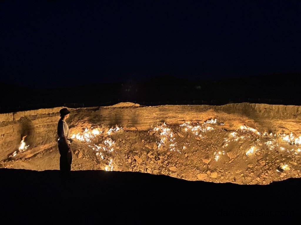 2 Day Turkmenistan Tour from Khiva to Darvaza Gas Crater Japanese tourist standing at night and admiring the burning Darvaza Gas Crater in Turkmenistan