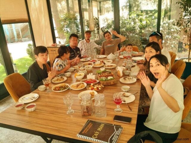 Tourists enjoying traditional Turkmen cuisine in Turkmenistan - Darvaza Tour group meal with local dishes and hospitality