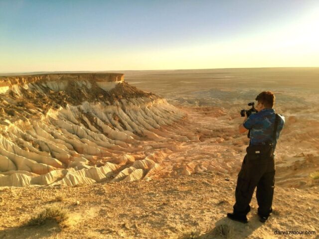 Stunning sunset view at Yangikala Canyon in Turkmenistan with dramatic golden light illuminating the colorful rock formations