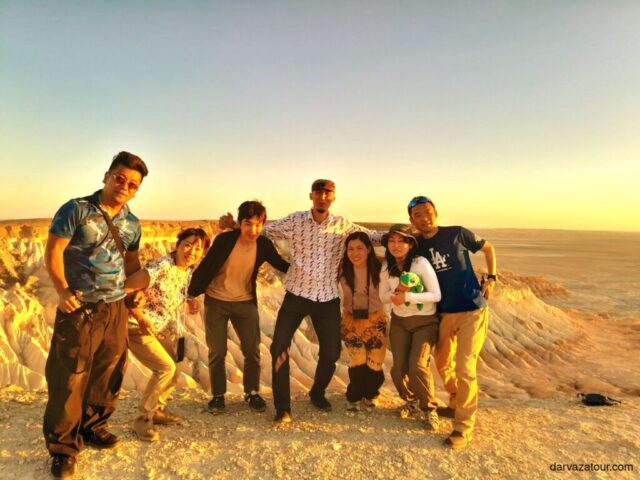 Japanese tourists and Turkmenistan tour guide enjoying scenic sunset view at the colorful rock formations of Yangikala Canyon