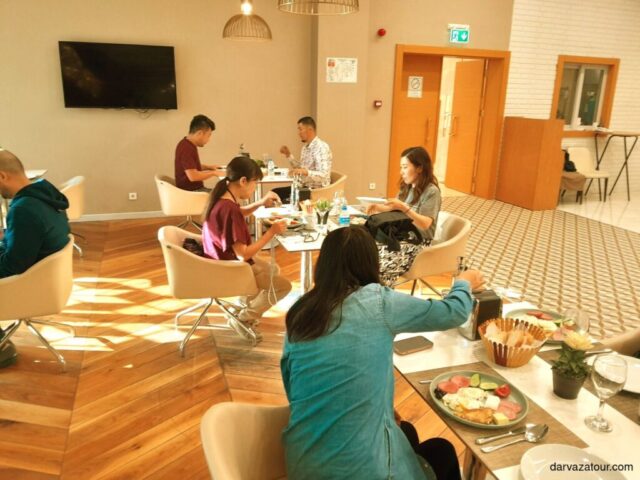 Tourists enjoying breakfast at hotel in Beyik Yupek Yoly, Turkmenistan. Delicious morning meal with coffee and pancakes during Turkmenistan tour.