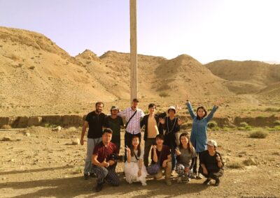 Tourist group exploring Karakum Desert in Turkmenistan during Darvaza tour - travelers with guide discovering desert landscape and local culture