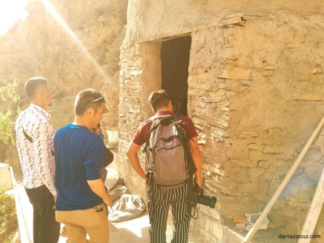 Tourists exploring ancient Gyz Bibi mausoleum in Nokhur Village, Turkmenistan - authentic cultural heritage site with traditional stone architecture illuminated by natural sunlight during Darvaza Tour
