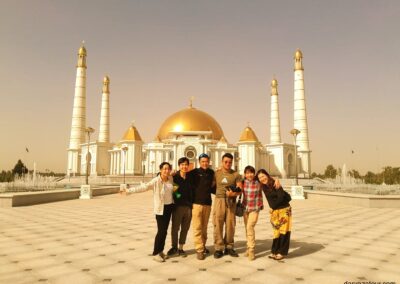 Group of tourists exploring white marble buildings and monuments in Ashgabat, Turkmenistan during a guided tour