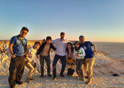 Happy Japanese tourist group with their Turkmen guide at Yangykala Canyon, Turkmenistan one of the most spectacular natural wonders of Central Asia, known for its colorful cliffs and breathtaking sunset views.