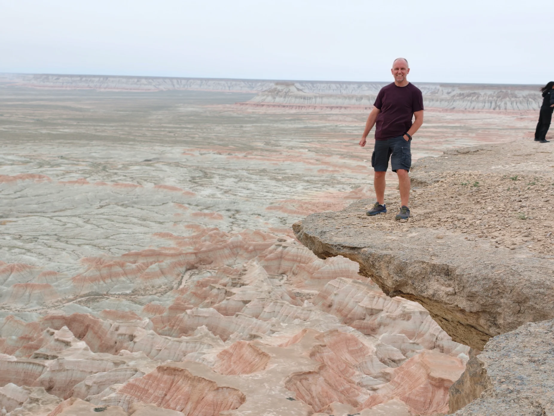 Traveler standing at a panoramic viewpoint above the colorful layered landscape of Yangykala Canyon in western Turkmenistan