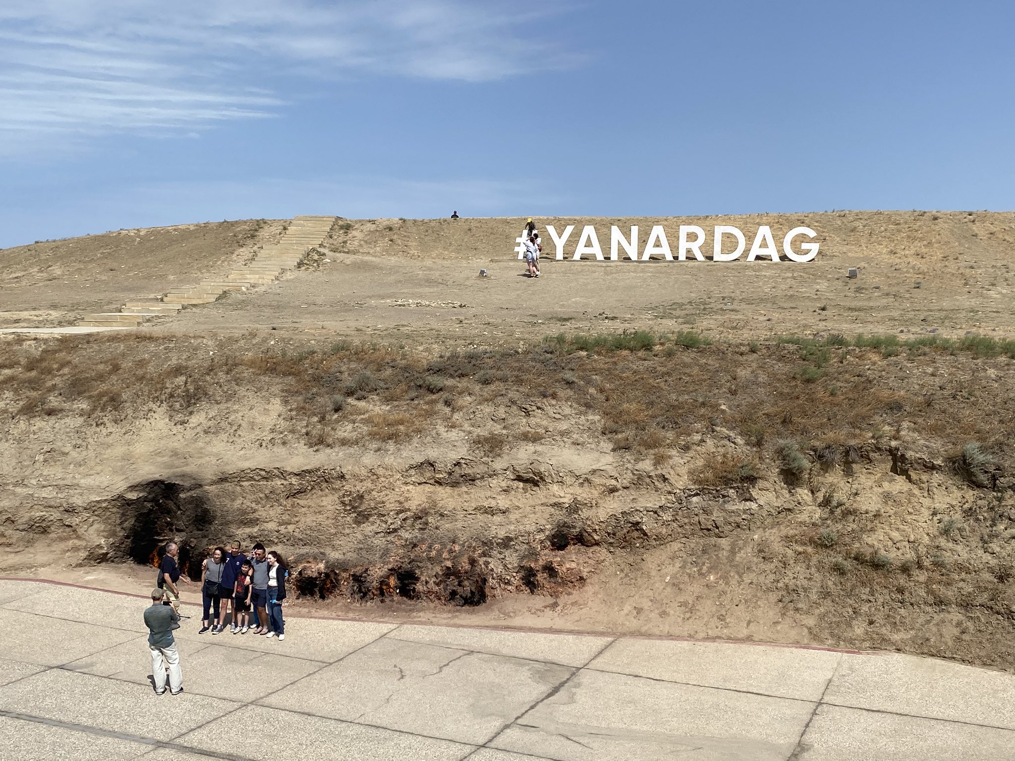 Tourists taking photos at Yanar Dag, a natural gas fire site in Turkmenistan, similar to the Darvaza Gas Crater but smaller.