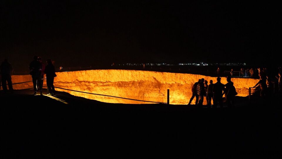 Group of around fifty tourists visiting Darvaza Gas Crater at night in December, Turkmenistan