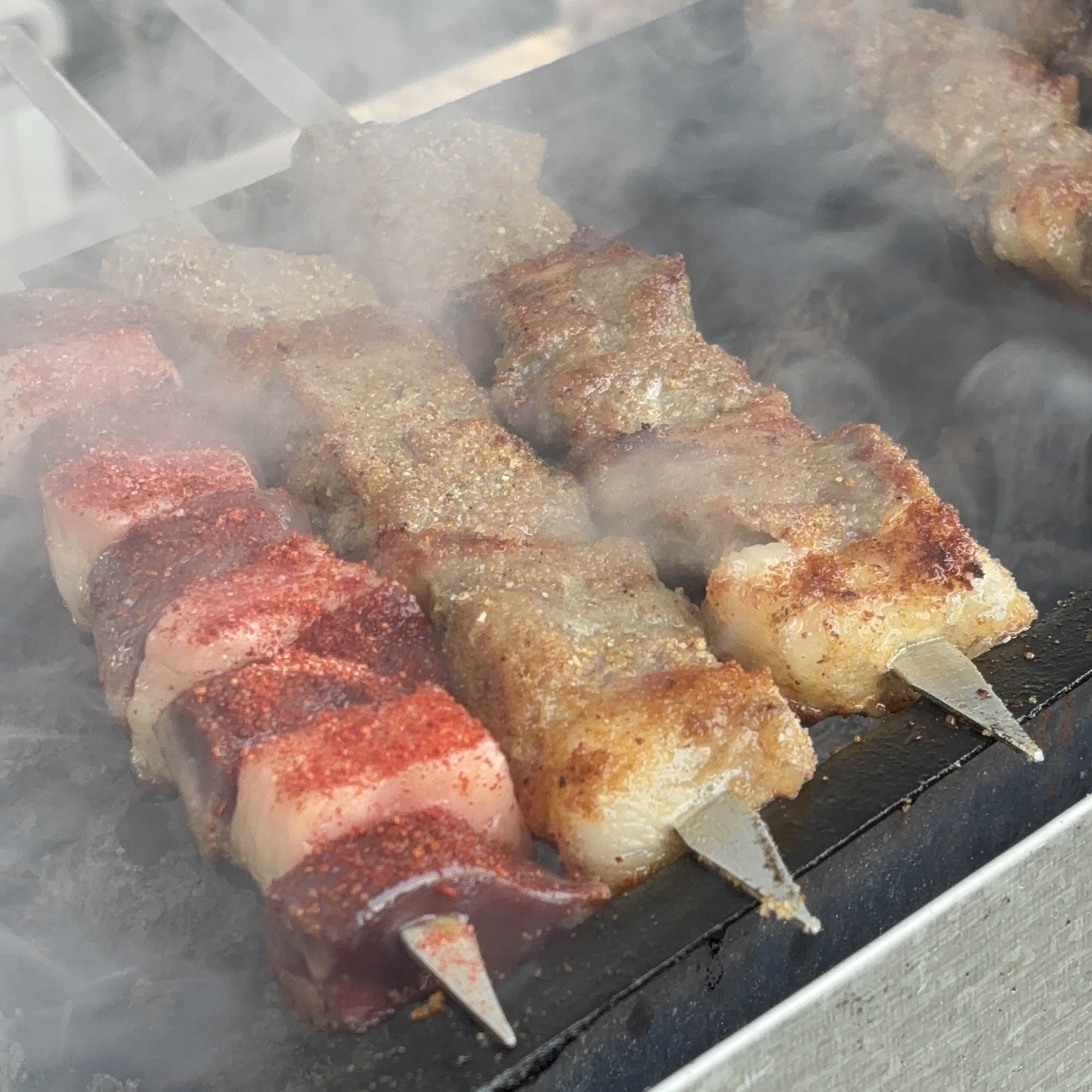 Turkmen lamb shashlik and liver with fat grilling on skewers over smoky charcoal, traditional street food in Turkmenistan.