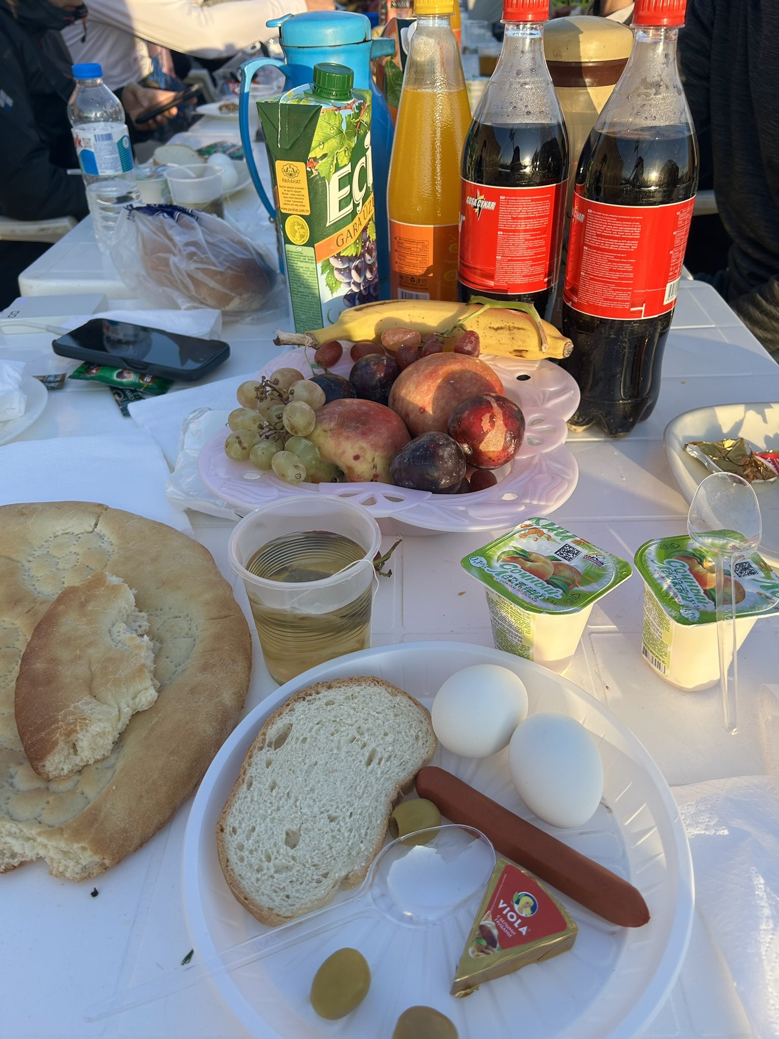 This photo shows the breakfast prepared in Darvaza for the group. It includes a sausage, two eggs, cheese, olives, yogurt, tandyr bread, fruit, tea, coffee, and other things tourists want. Some tourists are vegetarian, so they eat very little at breakfast.
