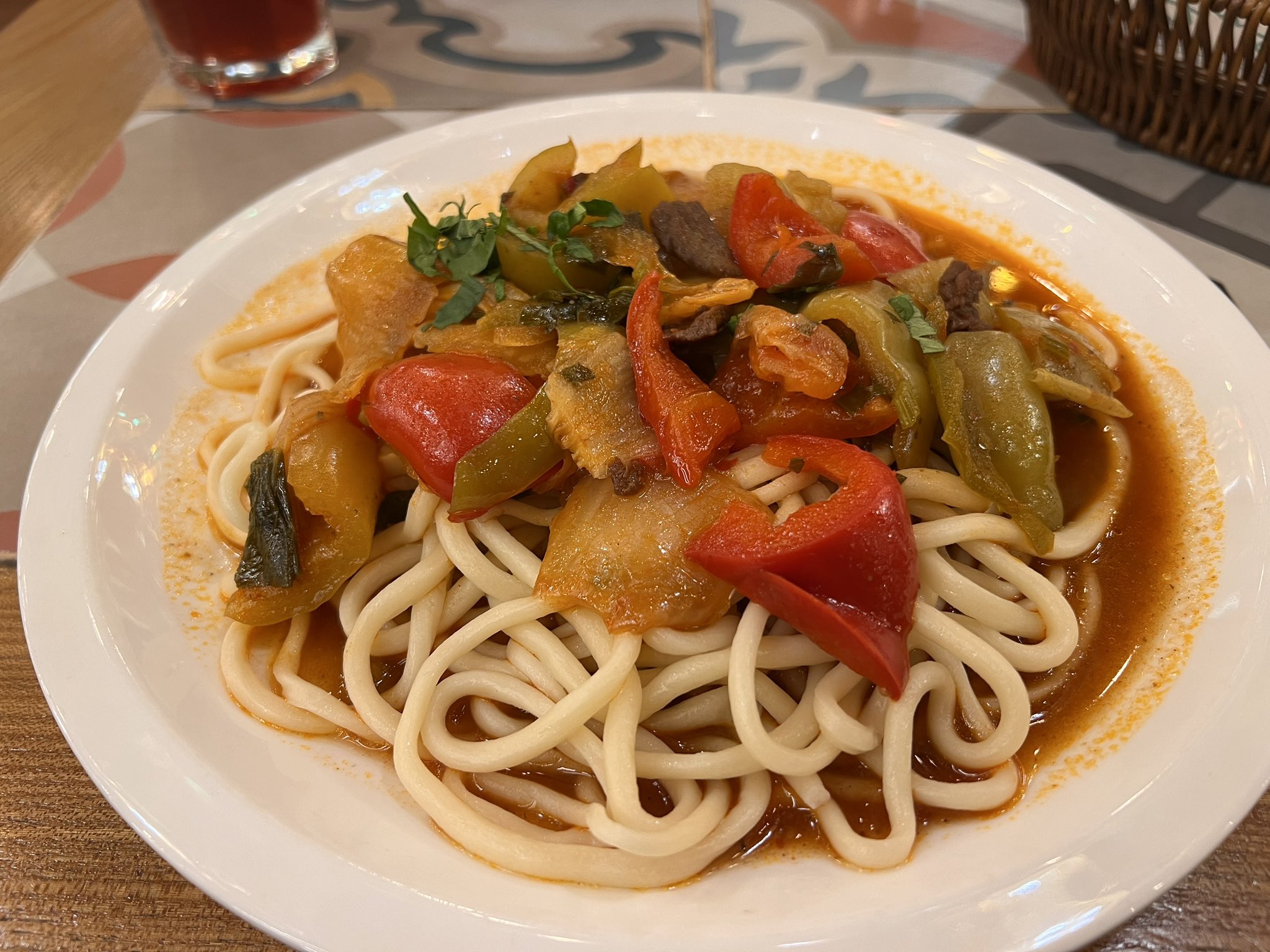 Plate of traditional noodle dish with vegetables and meat in tomato sauce, served in a national restaurant in Ashgabat.