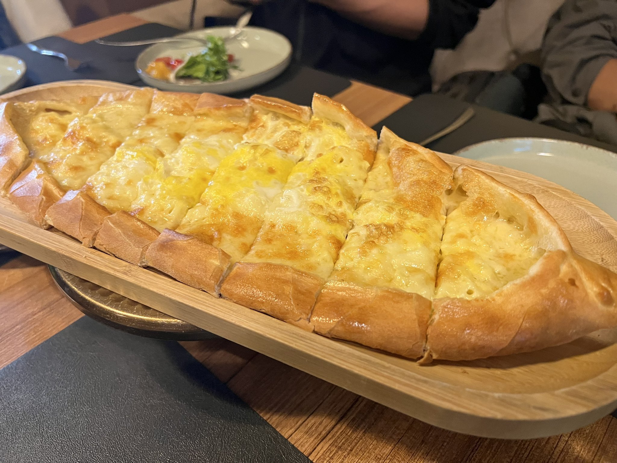 Cheese pide served on a wooden tray in Ashgabat restaurant, enjoyed by tourists.