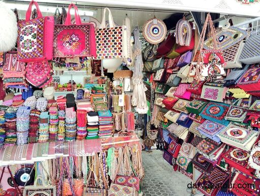 Colorful handmade Turkmen bags and souvenirs at Russian Bazaar in Ashgabat, showcasing traditional carpet patterns and embroidery