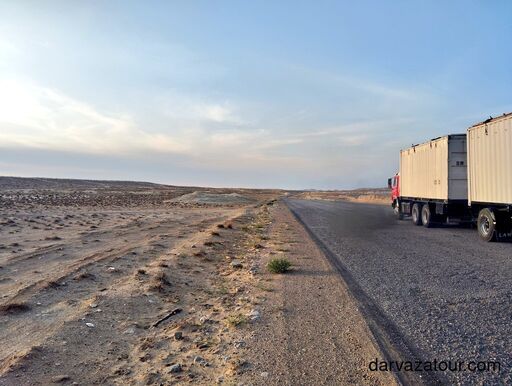 Desert highway to Darvaza Gas Crater in Turkmenistan with passing truck on the old asphalt road through the Karakum Desert