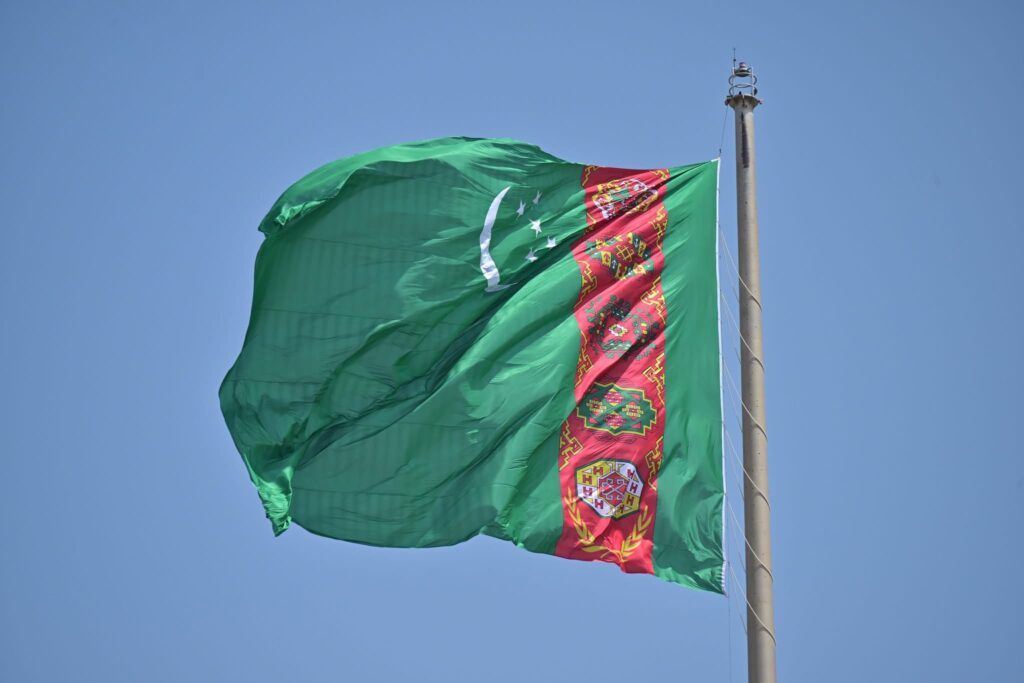 Turkmenistan national flag waving on a tall flagpole against blue sky