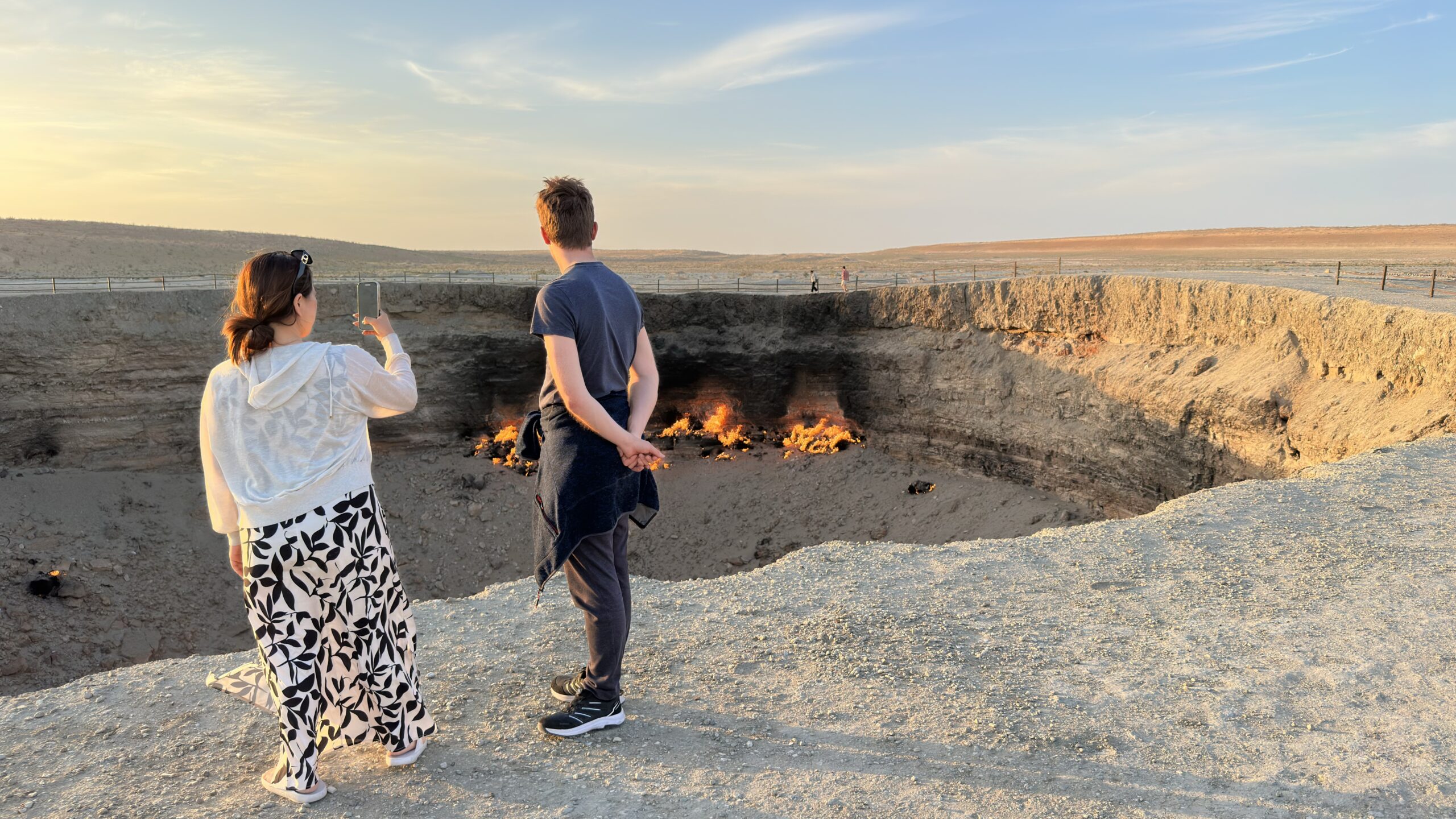 Darvaza Tour guide Guljan and a traveler viewing and photographing the flames of Darvaza Gas Crater in Turkmenistan