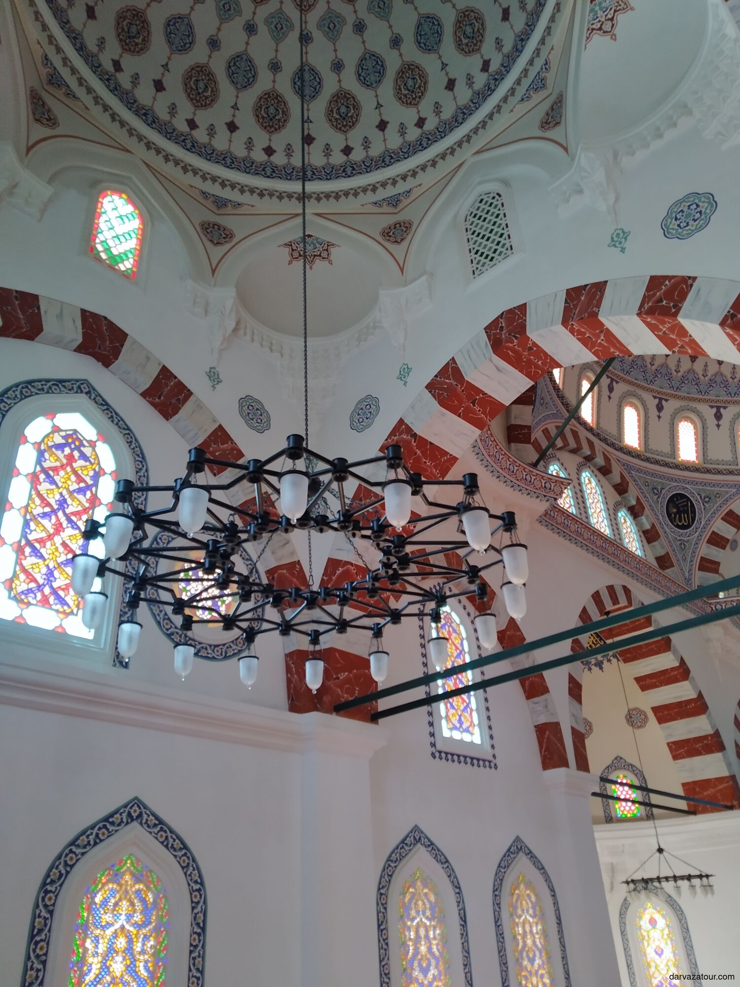 Interior of Ertugrul Gazi Mosque in Ashgabat, Turkmenistan — beautiful Ottoman-style dome with colorful stained glass windows and Islamic geometric patterns, built in the Turkish architectural style in the 1990s.