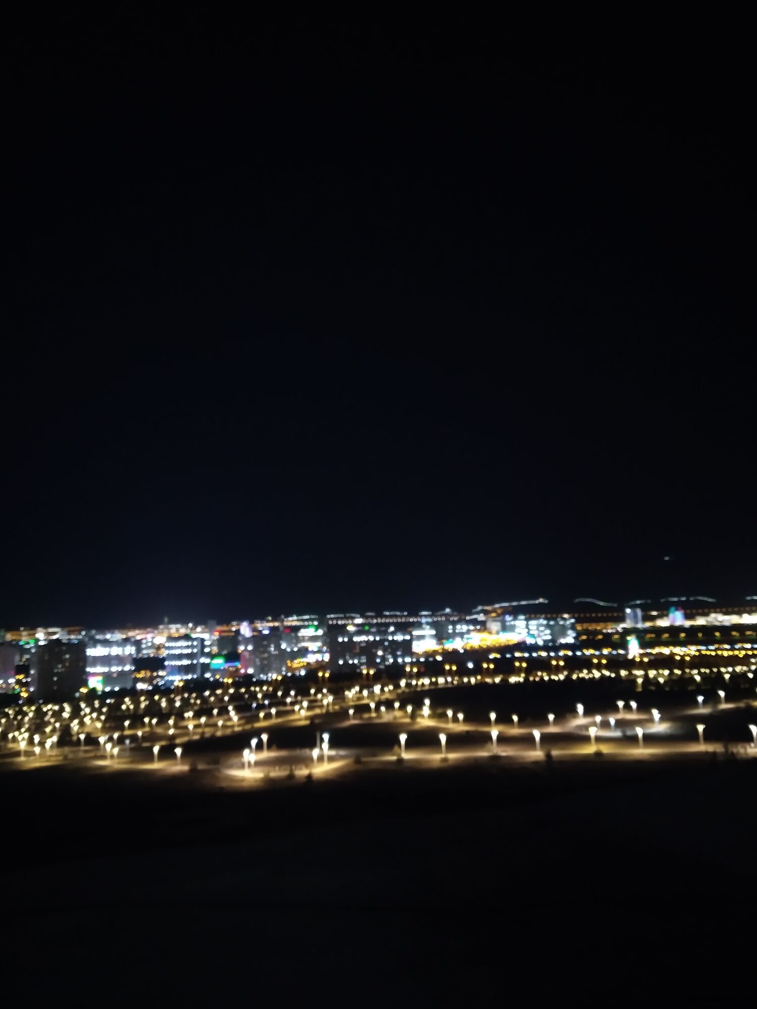 White marble buildings and tree-lined avenue in Ashgabat, Turkmenistan, at sunset.