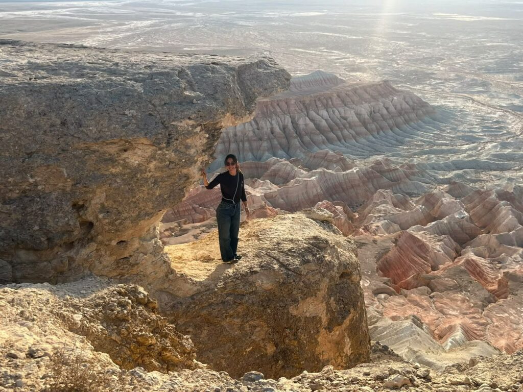 Traveller at the Rim of Yangykala Canyon Traveller standing on a rock ledge above the colourful layered cliffs of Yangykala Canyon