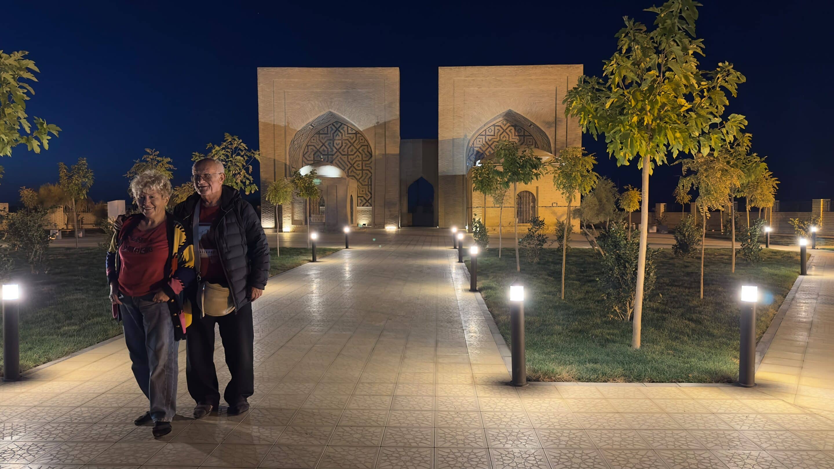 Two travellers at the illuminated Askhab Mausoleums at night in Ancient Merv, Turkmenistan