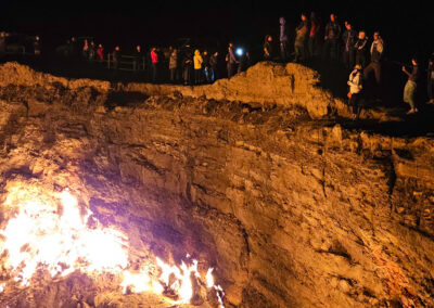 Tourists gathered around the Darvaza Gas Crater at night in Turkmenistan, watching the flames of the famous “Gates of Hell” during the New Year celebration.