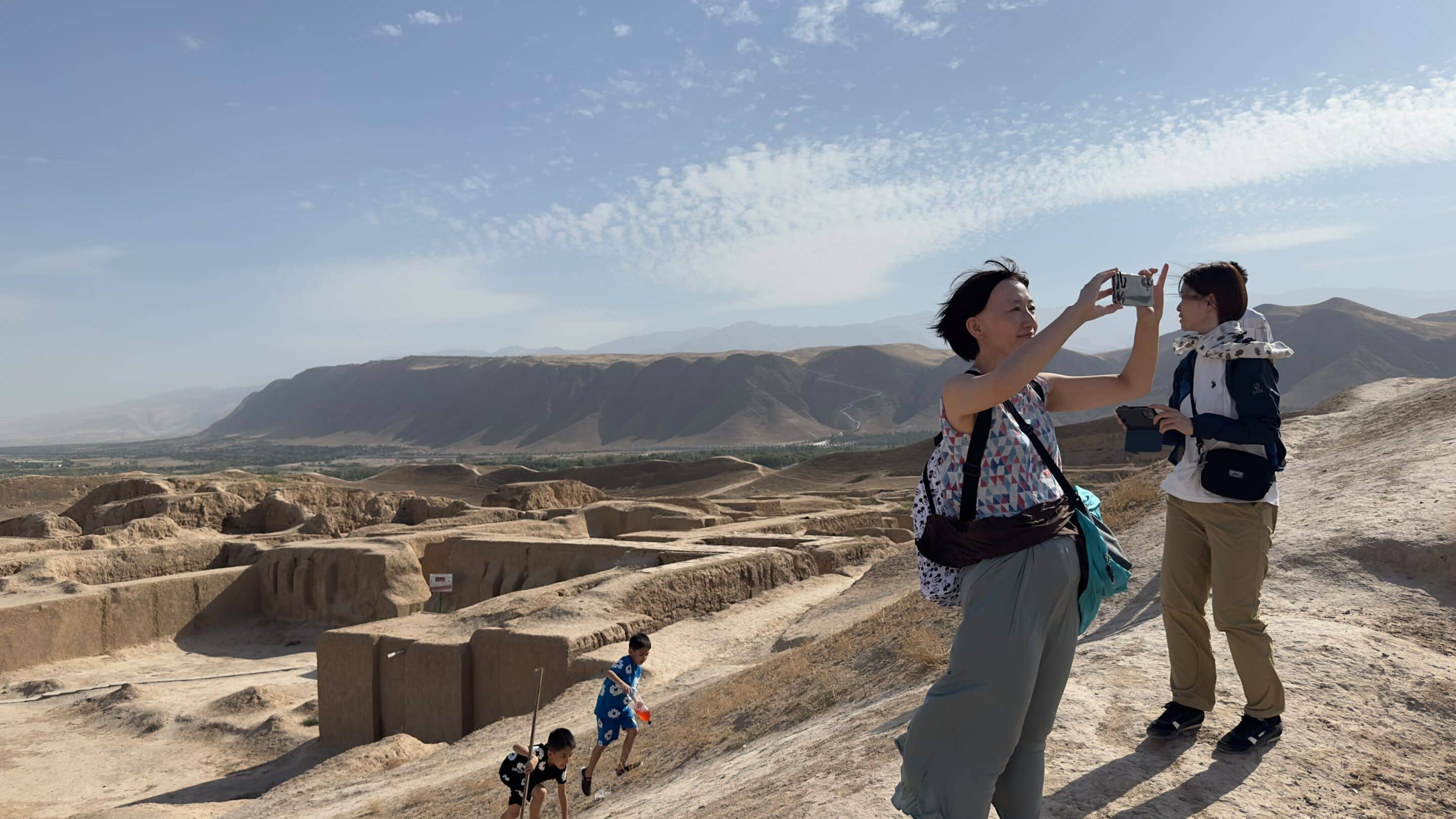 Traveller photographing the ruins of Old Nisa with the Kopetdag Mountains in the background near Ashgabat