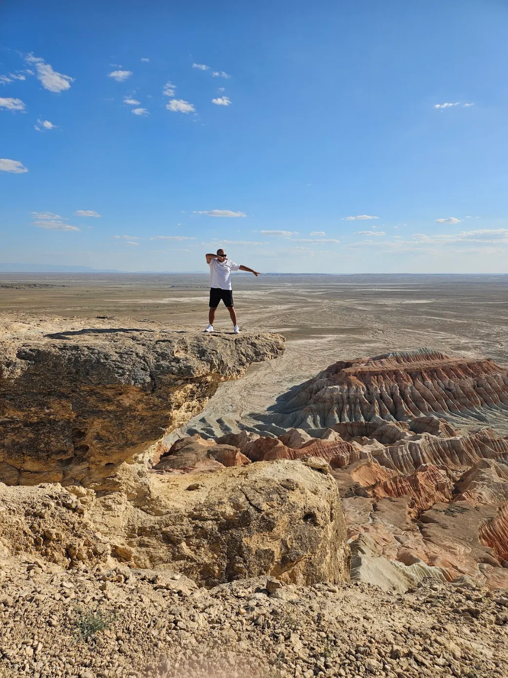 Traveller standing on a high cliff overlooking the dramatic multicolored landscape of Yangykala Canyon in Turkmenistan