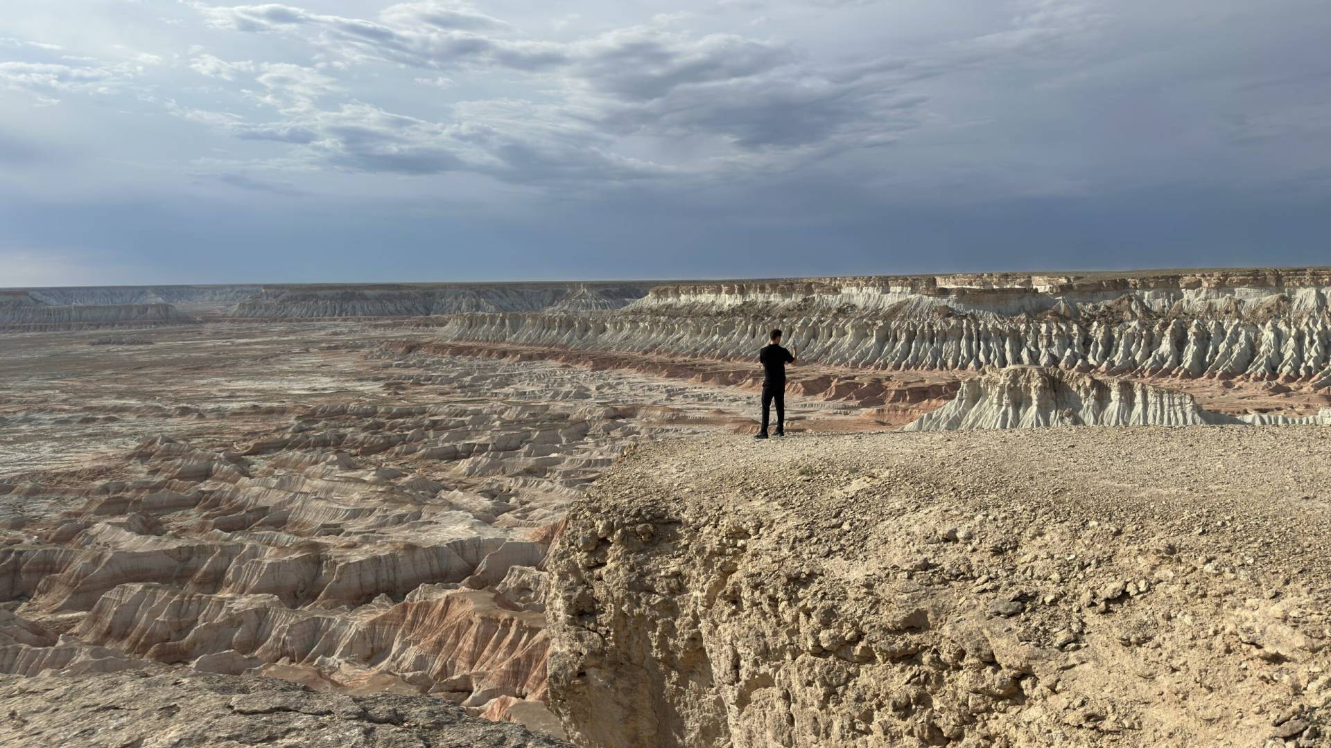 French tourist enjoying panoramic views of the dramatic cliffs and colorful formations of Yangykala Canyon in Turkmenistan