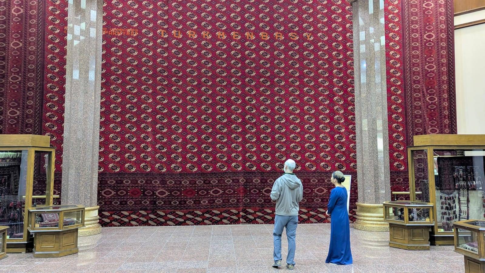 Visitor and museum guide viewing a giant traditional handwoven Turkmen carpet at the Carpet Museum in Ashgabat