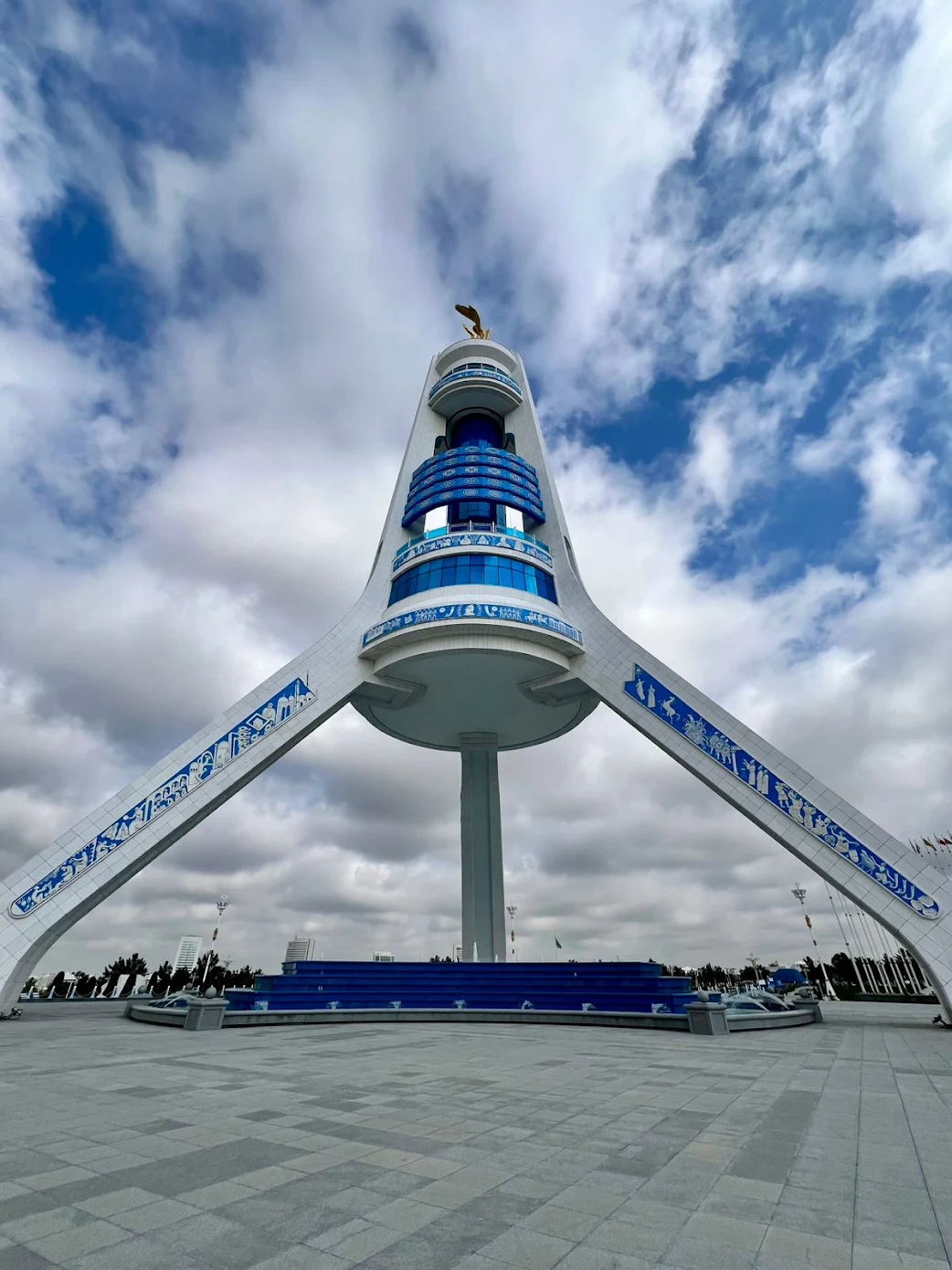 Monument of Neutrality in Ashgabat photographed from below beneath dramatic clouds and blue sky