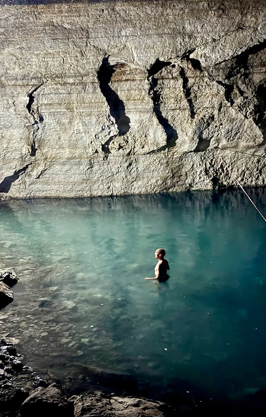 Traveler swimming in the turquoise thermal water of Kow-Ata underground lake inside a natural cave in Turkmenistan