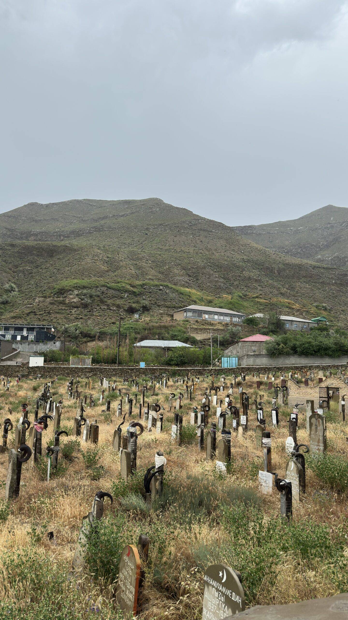 Traditional mountain cemetery with distinctive horn-shaped grave decorations in Nokhur village, Turkmenistan
