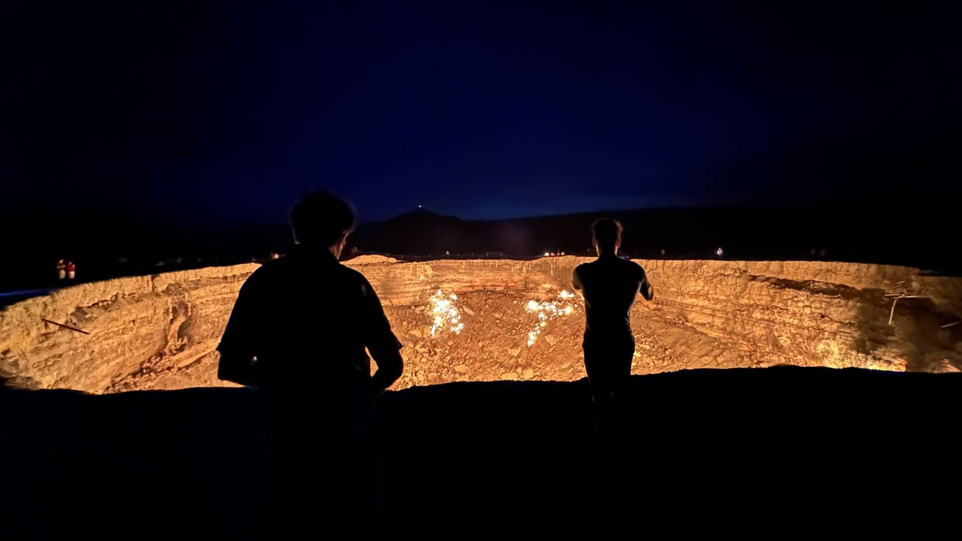 French tourists watching the glowing Darvaza Gas Crater at night in the Karakum Desert, Turkmenistan