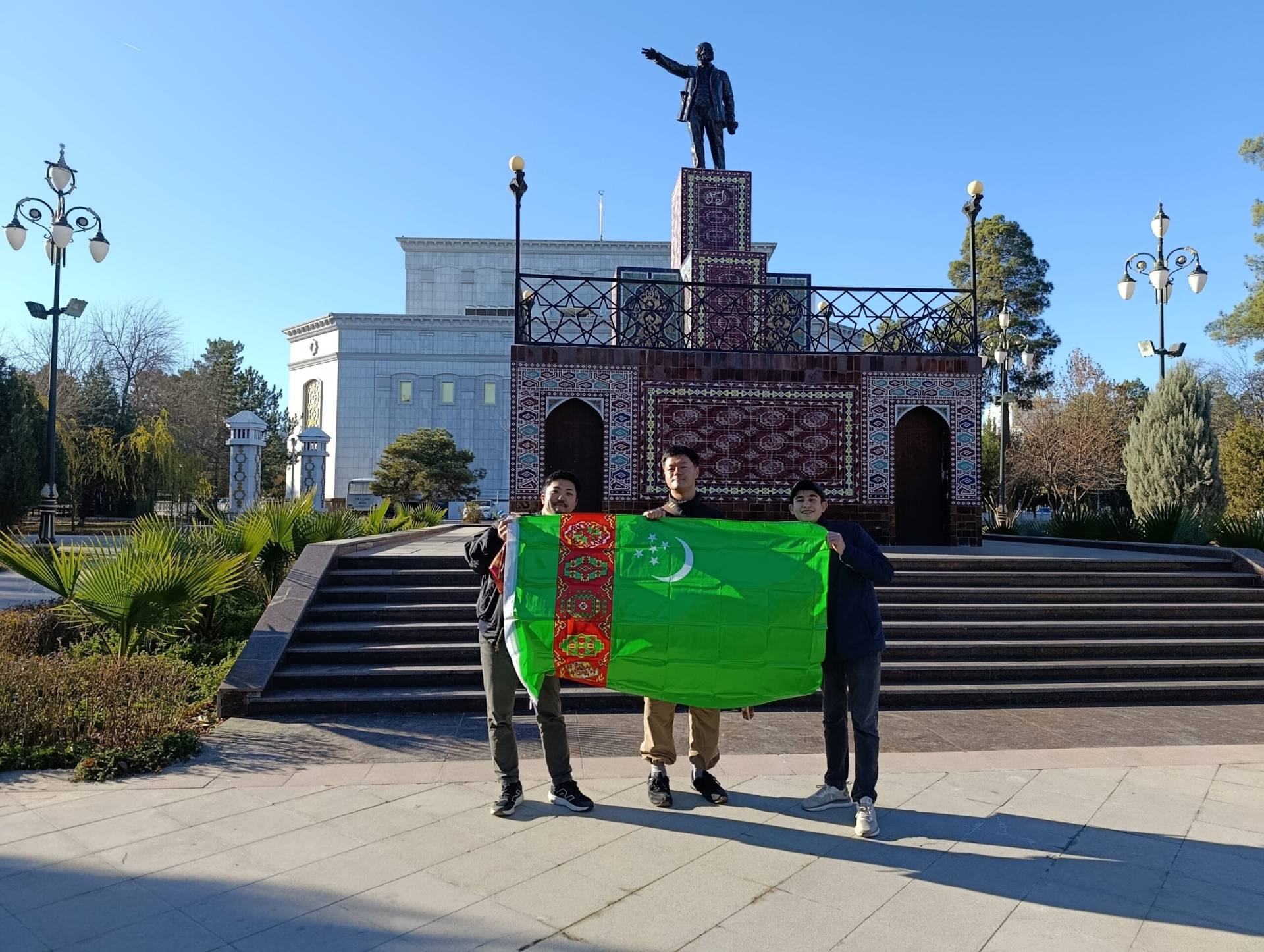 Japanese tourists and their guide holding the Turkmenistan flag in front of the Lenin Monument in Ashgabat